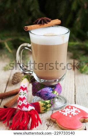 A glass of warm cacao with a small knit scarf and homemade gingerbread in the form of a red boot on a wooden table. Selective Focus on glass. Toned
