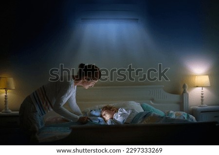 Air conditioner in bedroom. Kids room climate control. Mother and child in bed under cool air breeze. Comfortable temperature for healthy sleep on summer night. Air conditioning device in family home. Royalty-Free Stock Photo #2297333269