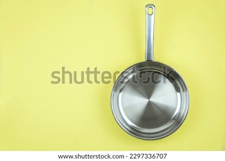 Frying pan on a yellow background. Cooking concept. Top view. Royalty-Free Stock Photo #2297336707