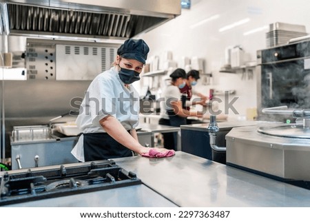 female cook cleaning her kitchen after work Royalty-Free Stock Photo #2297363487