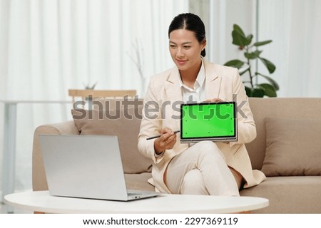Smiling businesswoman showing presenation on tablet computer to colleagues in online meeting