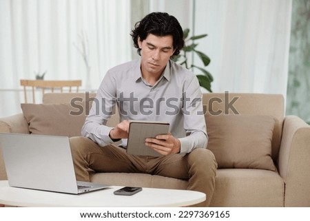 Serious entrepreneur reading article on tablet computer