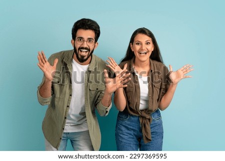Excited emotional beautiful loving indian young couple man and woman in casual outfits gesturing and exclaiming on colorful studio background, have great news, won jackpot