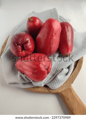 A group of malay apples or jambu bol (Syzygium malaccense). Served on wooden tray with napkin. It is known as a Malay rose apple, or simply Malay apple. Over white background. No people Royalty-Free Stock Photo #2297370989