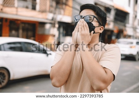 Asian young man wearing face mask to protect PM 2.5, protect pollution, anti smog and viruses on road in the city. Global warming concept. Healthcare concept. Environmental pollution concept. Royalty-Free Stock Photo #2297393785