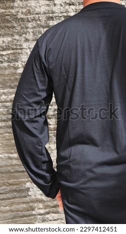 A moslem male model wearing plain black long sleeve t-shirt. Outdoor no face photography.