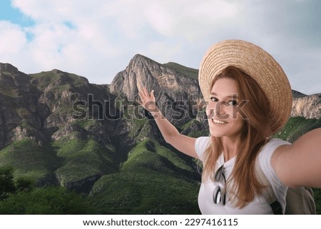 Beautiful woman in straw hat taking selfie in mountains