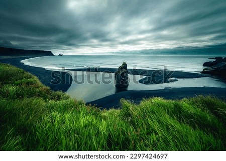 A beautiful landscape of Reynisfjara black sand beach with huge cliff and cloudy sky long exposure Royalty-Free Stock Photo #2297424697