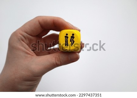 Hand holding dice with people need to pee symbolic icon communicating with no language by showing off where is the toilet or bathroom sign language silhouette