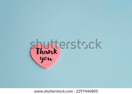 Thank you message on a pink heart sticky note on blue background  Royalty-Free Stock Photo #2297446805