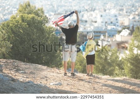 Retired man  and kid boy holding the flags of the USA and Ukraine on city  view