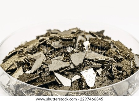 Manganese samples in petri dish, pure manganese metal flakes used in industry, isolated white background , macro photography Royalty-Free Stock Photo #2297466345