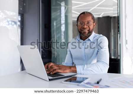 Portrait of mature businessman inside modern office, senior man in shirt smiling and looking at camera, worker using laptop at work Royalty-Free Stock Photo #2297479463