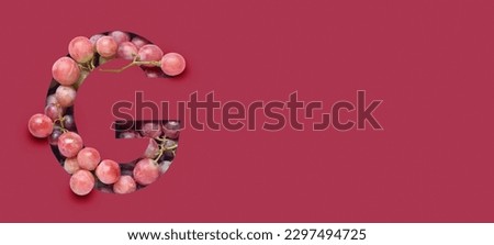 Letter G cut in viva magenta paper and ripe grapes. Banner for design Royalty-Free Stock Photo #2297494725