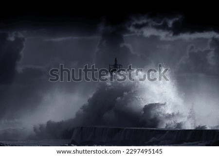Big storm wave against lighthouse of Vila do Conde, north of Portugal (enhanced sky), at sunset - Black and White toned blue