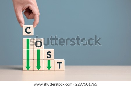 Lean or Cost reduction concept. Optimize manufacturing management. Decreasing company expense to maximize profits. Hand puts wooden cube with words cost and green down arrows. Business improvement. Royalty-Free Stock Photo #2297501765