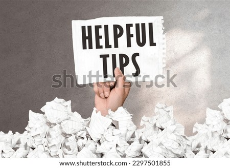 Hand holds a piece of paper with text Helpful tips on a gray wall background