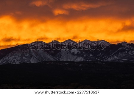 Bright Orange Clouds Backlight The La Sal Mountains AT Sunrise in Arches National Park Royalty-Free Stock Photo #2297518617