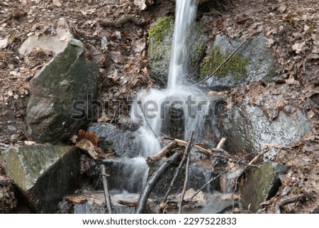 River course littered with rocks with waterfall in Siegerland Royalty-Free Stock Photo #2297522833