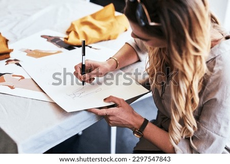 She has excellent drawing skills. a fashion designer working on new sketches at her desk.