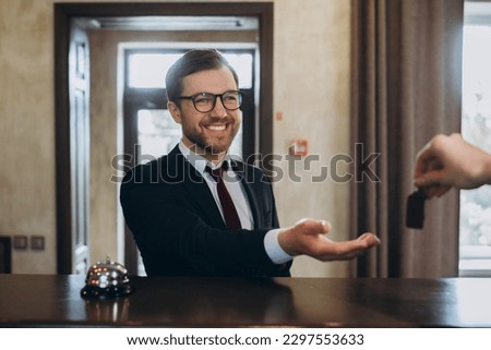 Smiling businessman takes door key after checking in hotel, selective focus.