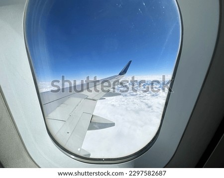 View to the aircraft wing from the window inside the plane. Flight over the snowy mountains range