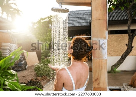 Woman taking an outdoor shower at a dream vacation resort.