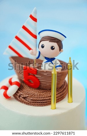 part of children's cake in the marine style decorated with a sailboat with a sailor. themed dessert for children's birthday