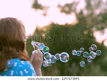 girl blowing soap bubbles outdoor, abstract natural background. rear view. dreaming, harmony peaceful atmosphere. Happy childhood concept. template for design