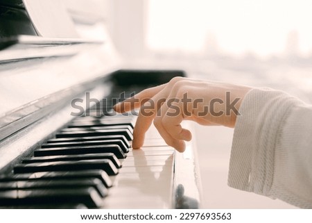 a woman touching piano key with left hand Royalty-Free Stock Photo #2297693563