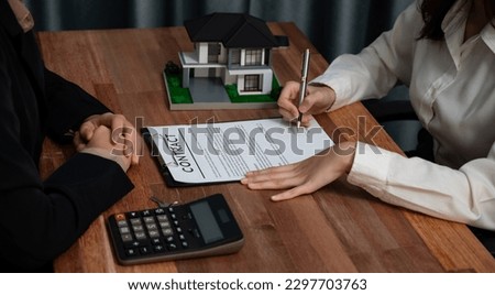 Completing the final step of the house loan process, the buyer signs the loan contract paper with a pen on the desk, securing the ownership of the property. Enthusiastic