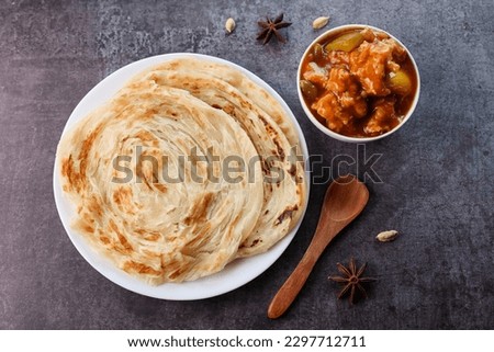 Chilly chicken with Kerala parathas porotta roti parotta barotta naan layered flatbread made from maida whole wheat flour. Eat with spicy Asian chicken beef egg curry gravy. Indian food. Royalty-Free Stock Photo #2297712711