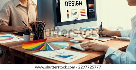 Graphic designer work on computer laptop and with graphic drawing pen while brainstorming unique design with professional graphic team in modern digital studio workplace. Panorama shot. Scrutinize