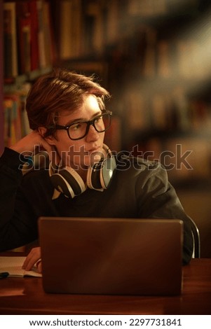 A smart student studies in a library sitting at a table with a laptop. Education. Modern students.