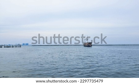 Old style wooden ship sailing towards the horizon on a calm sea and blue sky