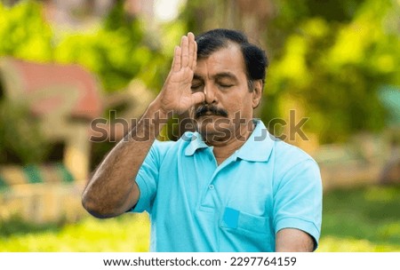Elderly Indian senior man doing nostril breathing yoga or pranayama exercise - concept of zen, healthy lifestyle and mental wellness Royalty-Free Stock Photo #2297764159