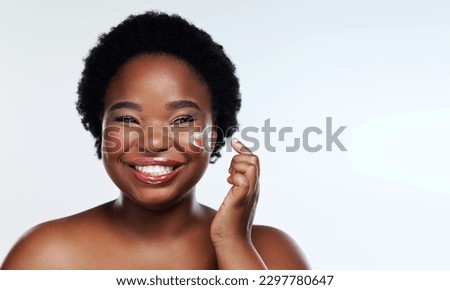 The moisturiser that keeps my skin happy. Studio shot of a beautiful young woman applying moisturiser to her face against a gray background.