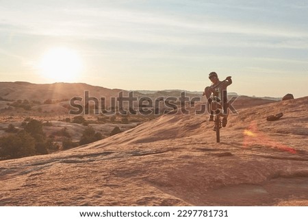 Staying fit doesnt have to be boring. Full length shot of a young male athlete popping a wheelie while mountain biking in the wilderness.