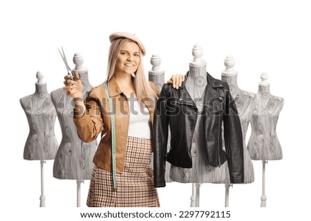 Female fashion designer leaning on a mannequin doll with a leather jacket and holding scissors isolated on white background Royalty-Free Stock Photo #2297792115