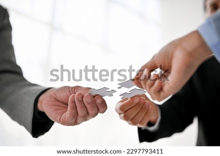 Close-up image of diverse businesspeople holding a piece of jigsaw puzzle, finding solutions, playing game during a team building meeting, supporting and teamwork. Royalty-Free Stock Photo #2297793411