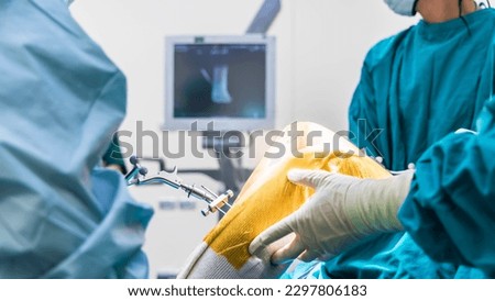 Doctor or surgeon in blue gown used robotic navigator total knee joint arthroplasty surgical instrument inside operating room.Medical technology in orthopedic surgery.Hand of people with a computer. Royalty-Free Stock Photo #2297806183