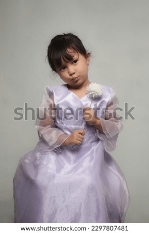 Cute and adorable expression from little girl, studio shoot, isolated in gray background