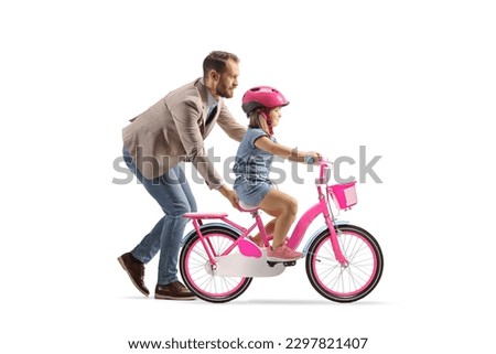 Profile shot of a father teaching a girl to ride a bicycle isolated on white background