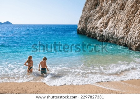 Happy kids looking at turquoise sea water at Kaputas beach, Lycia coast. Summer relaxing day at family vacation in Mediterranean Sea, Kas, Antalya region, Turkey