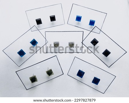 A black,blue colours,square shape earrings on white background. These earrings are attached to seven cards.These earrings made of resin material. These earrings are really beautiful.Shining.Attractive
