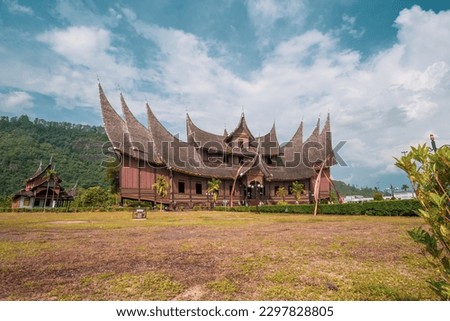 The view of dry meadow in front of Pagaruyung Palace (the traditional Minangkabau Rumah Gadang vernacular architectural style) with blue sky and white clouds background