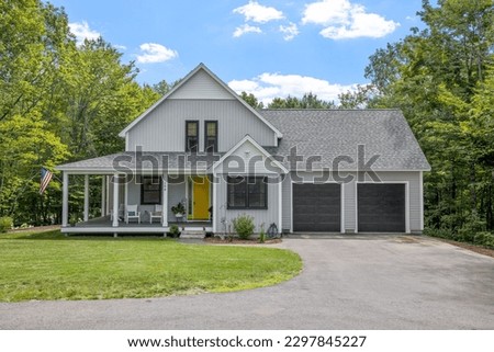 A modern custom new England colonial home with an American flag on a sunny day Royalty-Free Stock Photo #2297845227