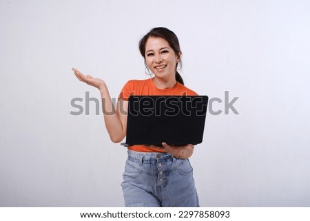 Photo of smiling female Asian hold laptop with hands open palms gesture showing empty space or copy space for product isolated on white background