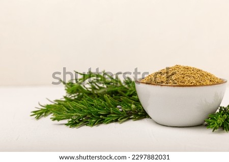 Dried rosemary in a bowl and branches of fresh rosemary on a vintage white wooden background. Spicy spices for cooking meat and fish. Recipe. Fresh rosemary herb. Place for text, space for copy.
