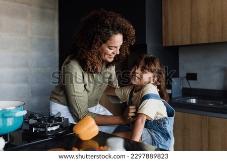 young latin single mother and child daughter cooking at kitchen in Mexico Latin America, hispanic family at home Royalty-Free Stock Photo #2297889823